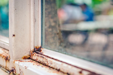 Close up of rust on an old white iron window in the corner of the frame with a blurred background