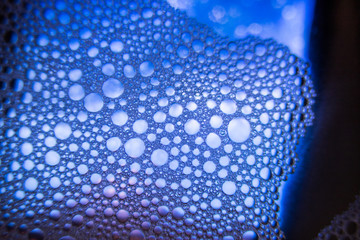 Colorful oil drops on a water surface with blue colour