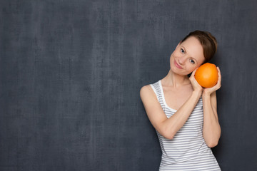 Portrait of happy woman holding fresh grapefruit in hands and smiling