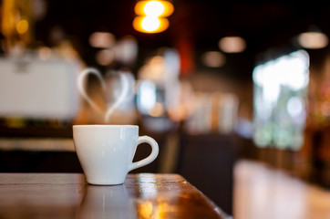 Hot Coffee Cup on Wood Table in blurred Coffee Shop background.