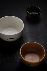 Set of three handmade ceramic bowls. Matte black wood background