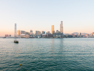 Fototapeta premium Tsim Sha Tsui Waterfront from the Wan Chai Ferry Pier, Hong Kong. Beautiful sunset shot of the South China Sea and buildings in the background (Cultural art center, K11 Musea, etc...). 