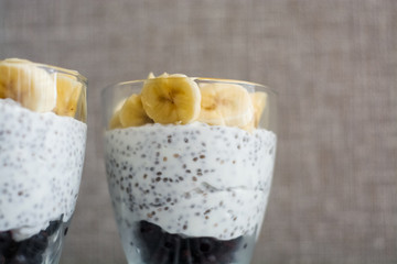 Background and two glasses with pudding chia, blackcurrant and fresh pieces of banana. Useful and delicious, with vitamins breakfast.
