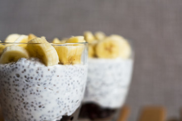 Background and two glasses with pudding chia, blackcurrant and fresh pieces of banana. Useful and delicious, with vitamins breakfast.