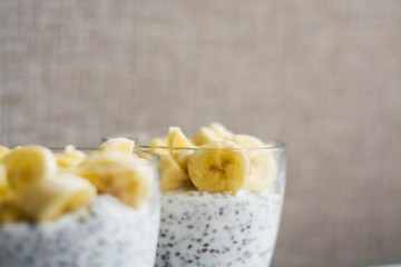 Background and two glasses with pudding chia, blackcurrant and fresh pieces of banana. Useful and delicious, with vitamins breakfast.