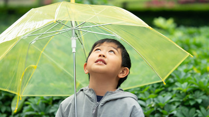 One cute and healthy Asian boy is looking up to the sky through the bright and clear yellow...