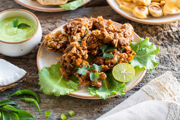 Indian cuisine. pakora traditional Indian deep-fried snack. pakoras on black plate with coconut chutney sauce curry leaves. national appetiser authentic vegetarian food. Asian travel food.