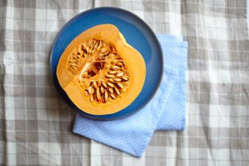 Pumpkin half on a blue plate on a table, top view