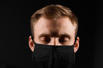 Obraz premium Handsome man in black t-shirt wear black medical mask, gray background. Coronavirus covid-19 quarantine period concept.