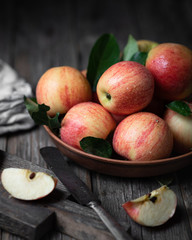 red apples in a ceramic plate on a dark wooden background