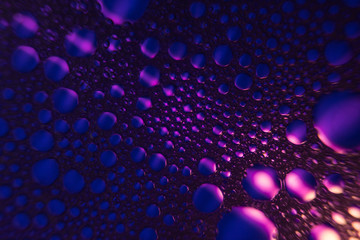 Close up of a water drops on a purple and black bubbles gradient background, covered with drops of water