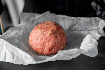minced meat on paper, stone tray, black gloves