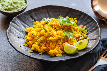 Indian cuisine. Poha or flattened rice typically Western Indian breakfast on black plate with coconut chutney sauce. national authentic vegetarian food. Asian travel food