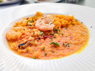 Tasty risotto with Shrimp, fresh herbs vegetables on a white plate