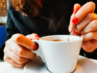 Woman holding white cup of hot coffee