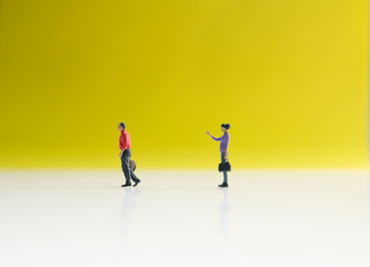 Two mini figure of businessman and businesswomen with yellow background. Business and working concept. 