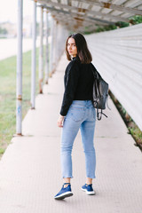 Beautiful girl in a black sweatshirt and blue jeans posing on a city street