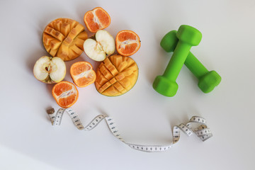 getting ready for summer with a sports diet. fruits, sentiment and dumbbells on a white background