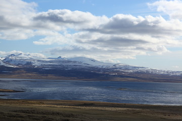 Snow-covered mountain in the middle of the ocean. Rain gloomy sky