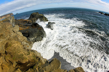Ocean wave with foam breaks on the coastal rocks in Iceland