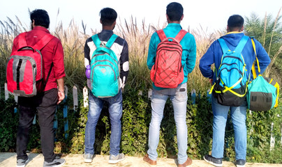 backside of four young boys with hanging bags in the park