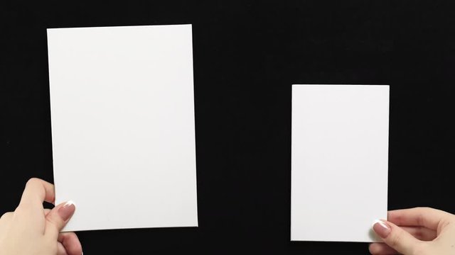 Advertising card mockup. Woman hands showing two white empty paper notes with copy space on black.