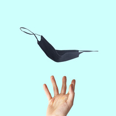 Obraz premium One black protective face mask with hand to prevent fast spreading coronavirus, originating in Wuhan, China, on cyan background.