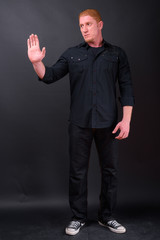 Full body shot of muscular man with orange hair showing stop gesture