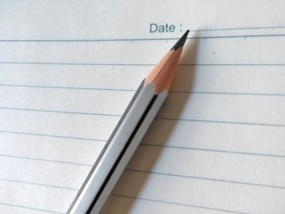 Pencil on white background. Pointed pencil on line paper. Line and pencil close up view. Writing...