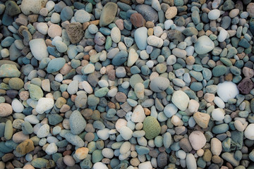 Background of sea pebbles. Abstract wallpaper of stones on the ocean. Multi-colored pebbles.