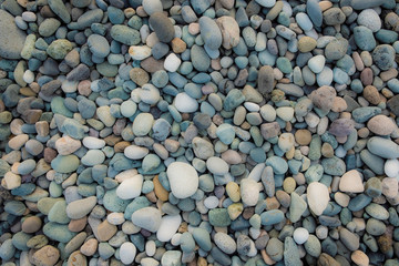 Background of sea pebbles. Abstract wallpaper of stones on the ocean. Multi-colored pebbles.