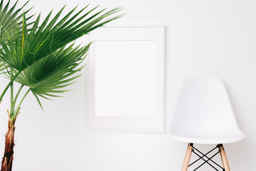 Large white frame mockup on white wall. Palm leaves. Simple modern interior. Art template. Background. Print mockup, posyter mockup