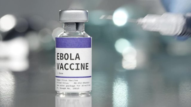 Ebola vaccine vial in medical lab with syringe placed next to it.