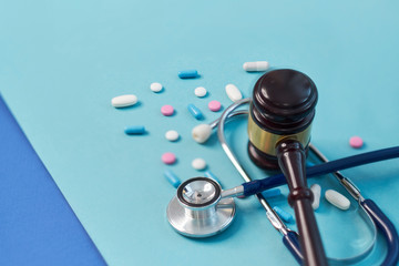 brown gavel and a medical stethoscope on blue background. symbol photo for bungling and medical error