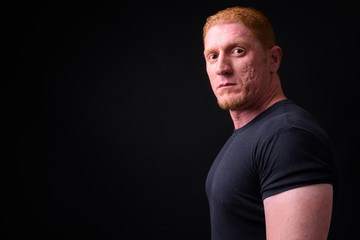 Profile view of muscular man with orange hair looking at camera