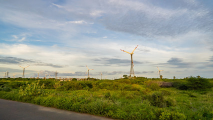 windmills for electric power production in the green field of wheat