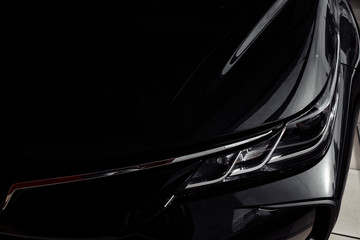 headlight of modern prestigious black car close up. Close up photo of modern car, detail of headlight. Headlight car Projector LED of a modern luxury technology and auto detail. selective focus