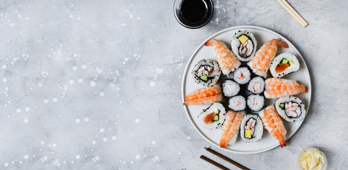 food delivery set of sushi and rolls with salmon and shrimp on a gray table. Top view of sushi, uramaki, hosomaki and nigiri.