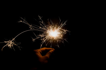 hand holding firework sparkles with light trail with bright orange light with black isolated background