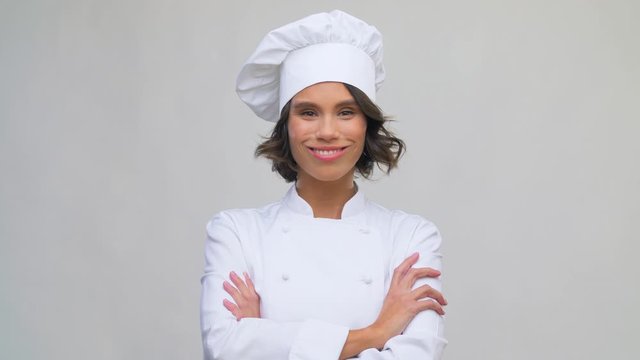 cooking, culinary and people concept - happy smiling female chef in toque over grey background