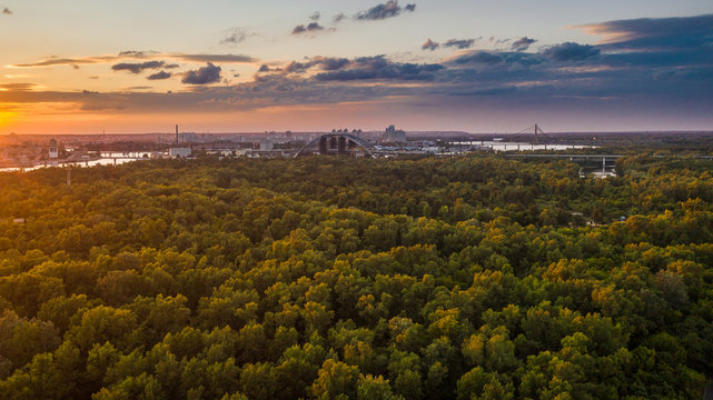 An aerial view is taken with a drone of sunset on summer time in Kyiv (Kiev) city. Skyline with a bridge in construction above the Dniepr river.