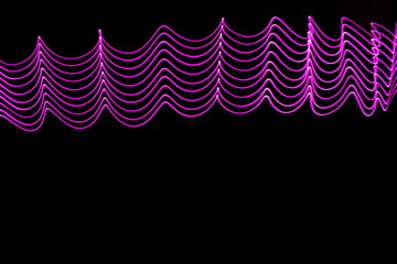 Long exposure photograph of neon purple colour in an abstract swirl, parallel lines pattern against...