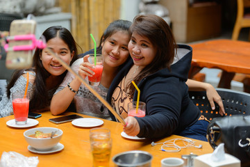 Group of young Asian women as friends taking selfie together outdoors