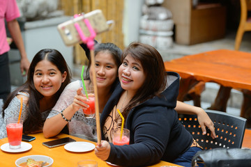 Group of young Asian women as friends taking selfie together outdoors