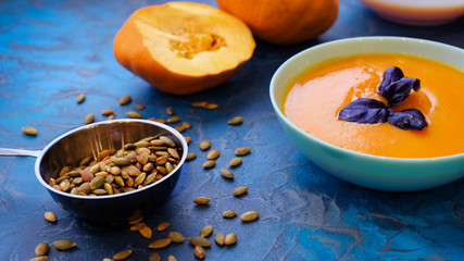 pumpkin soup with purple Basil on a blue background. Top View