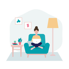 Woman sitting on an armchair with laptop  in her living room in period of self isolation and social distancing during Covid-19 virus epidemic. Stay at home concept. Freelance or studying concept.