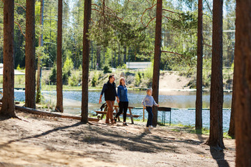 Side view of happy family of three walking near lake in countryside, parents holding hands and laughing