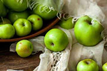 Green organic healthy apples in bowl on wooden board. Healthy food