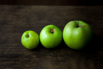 Green organic healthy apples in bowl on wooden board. Healthy food