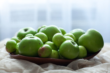 Green organic healthy apples in bowl on wooden board. Healthy food